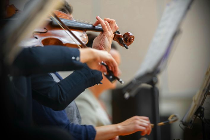 Detailed view of violinists in a live performance, showcasing orchestral musicianship.